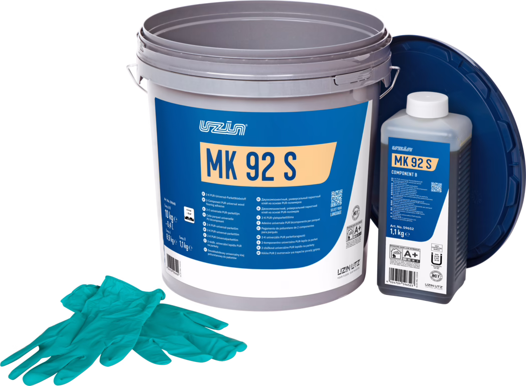 UZIN_Dummy_MK 92 S-10kg_2024-09 Photo produit en studio d'un kit de colle pour parquet : un grand seau en plastique gris avec une étiquette bleue marquée 'MK 92 S', une petite bouteille rectangulaire à droite indiquée 'MK 92 S Component B' avec un bouchon blanc, et un couvercle bleu foncé appuyé à l'arrière. Une paire de gants jetables turquoise est posée au premier plan. Les articles sont disposés sur un fond blanc épuré et éclairés de manière homogène, mettant en valeur les détails de l'emballage et les informations du produit pour la pose de sol.